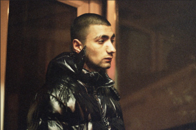 a man in a black leather jacket looking off into the distance