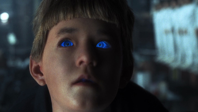 a young boy with blue eyes stares into the distance