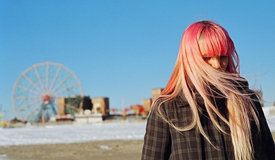 a woman with pink hair standing in front of a ferris wheel