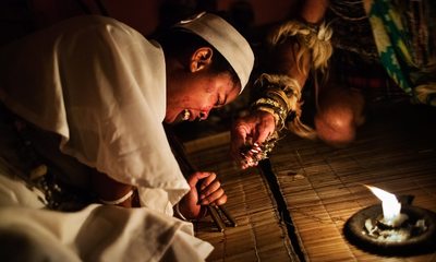 a man lighting a candle on a bamboo floor