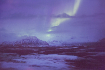 the aurora bore is visible in the sky above the mountains