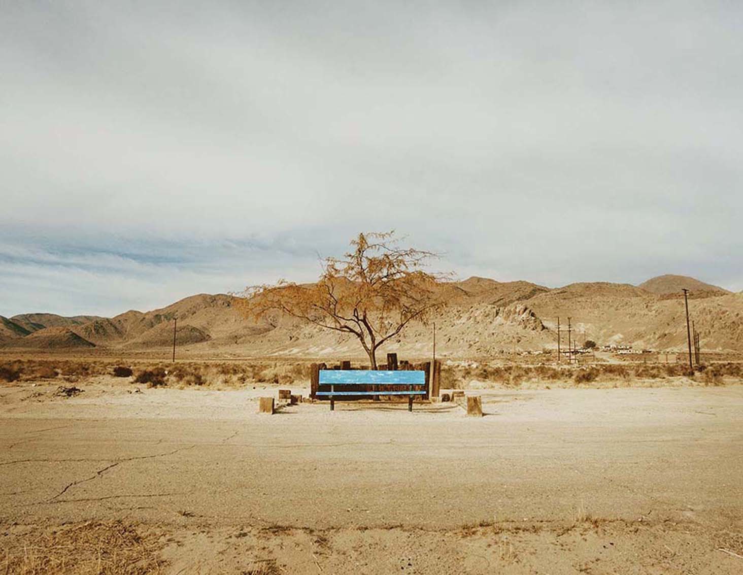 a blue bench sitting in the middle of a desert