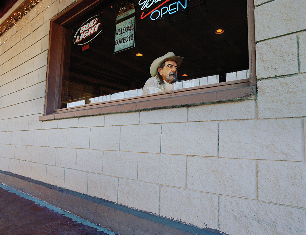 a man in a cowboy hat looking out a window