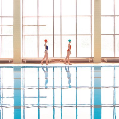 two women in swimsuits walking along a swimming pool