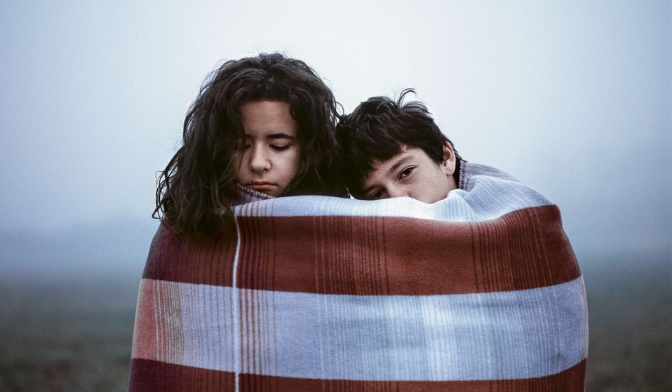 two people wrapped in a blanket in a field