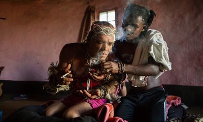 a man sitting next to a woman smoking a cigarette