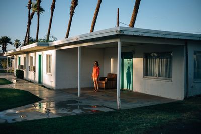 a woman in a red dress standing in front of a house