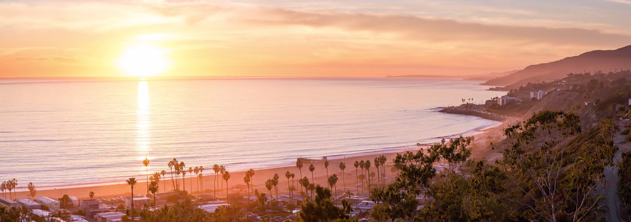 the sun is setting over a beach with palm trees