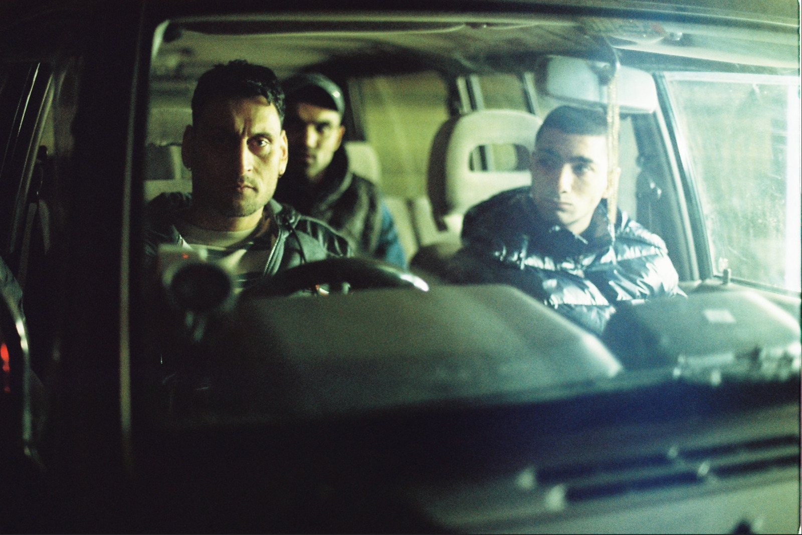 a group of men sitting in the back of a car