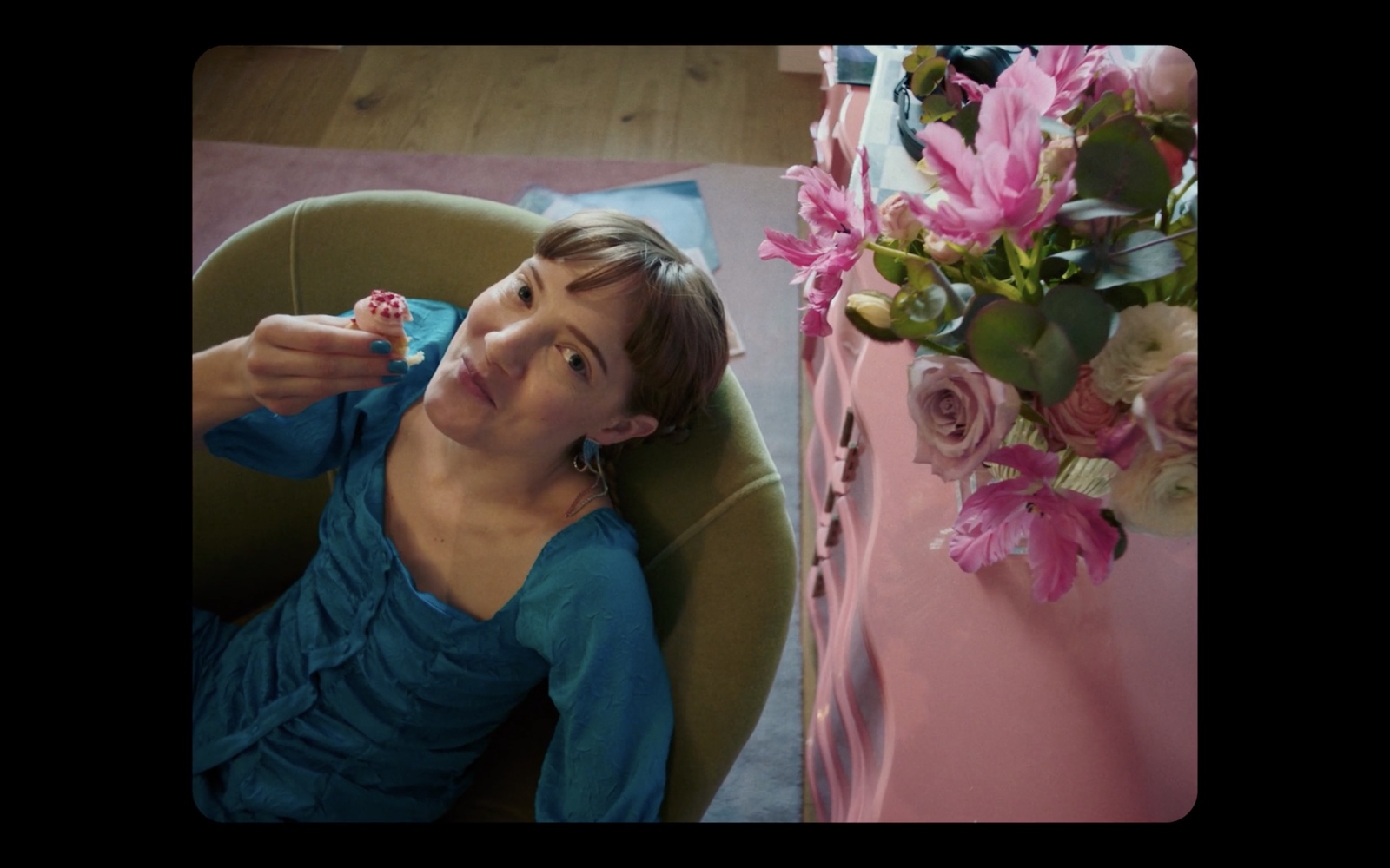 a woman sitting in a chair next to a vase of flowers