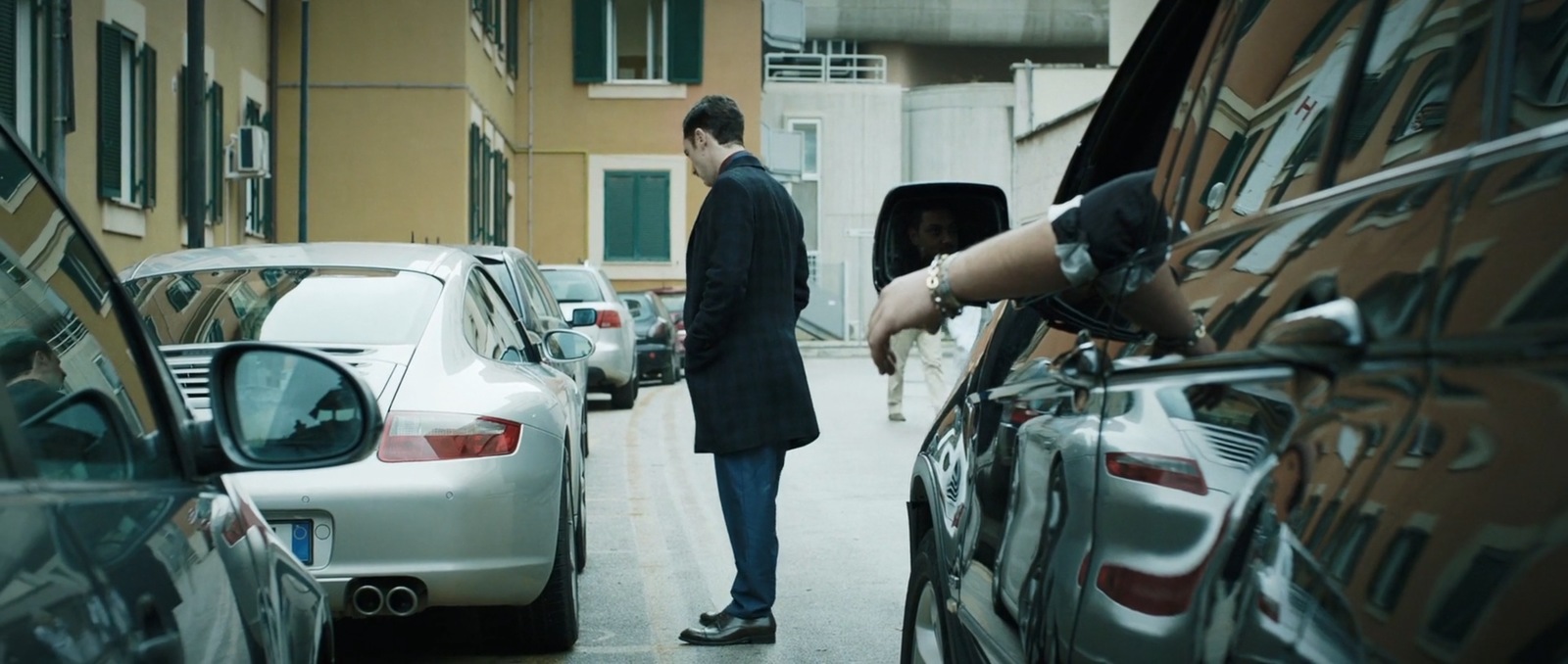 a man standing next to a parked car in a parking lot