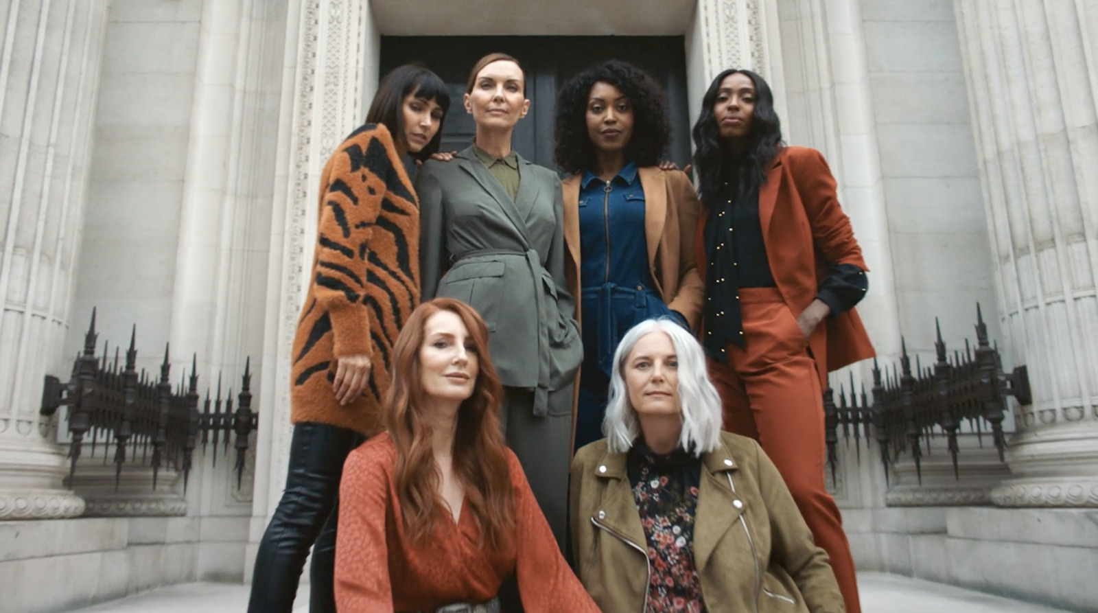 a group of women standing next to each other in front of a building