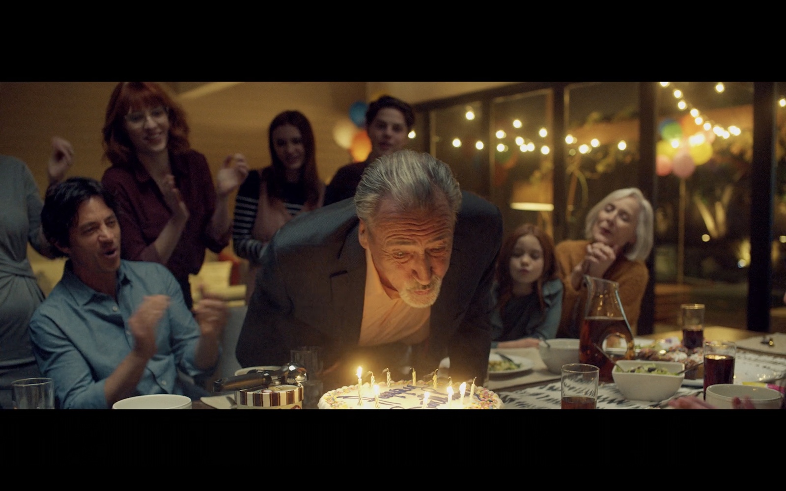 a man blowing out candles on a cake