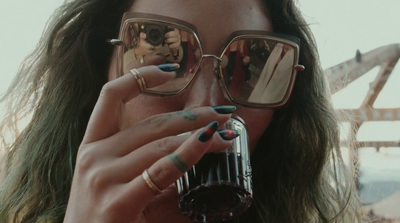 a woman holding a glass of wine while talking on a cell phone