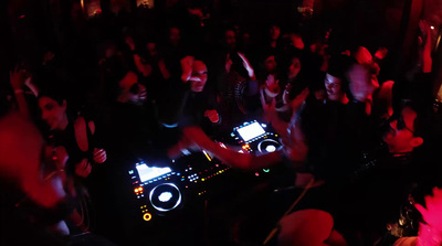 a group of people in a dark room with dj's