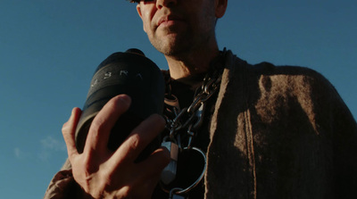 a man holding a camera with a chain around his neck