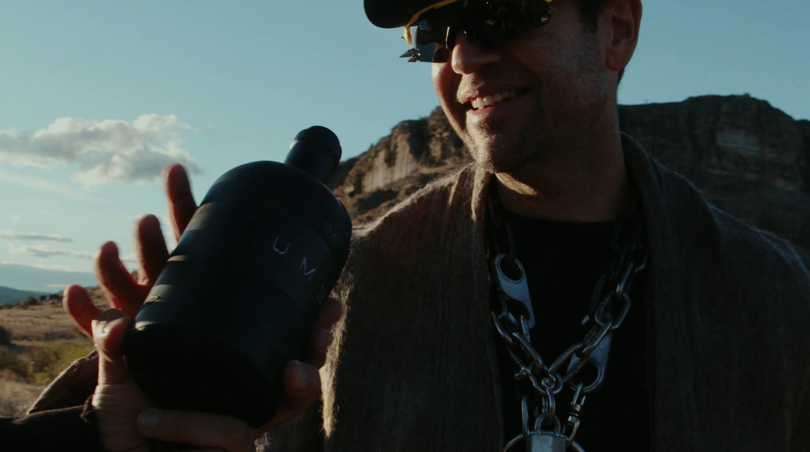 a man in a hat and sunglasses holding a black object