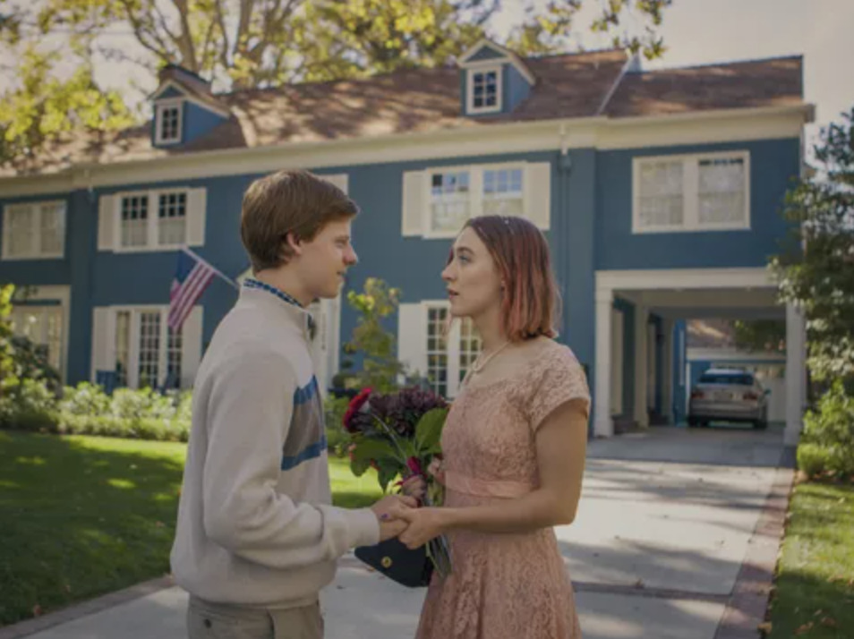 a boy and a girl standing in front of a blue house