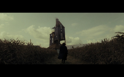 a person walking down a dirt road next to a tall building