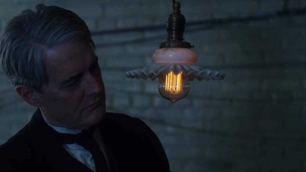 a man in a tuxedo looking at a light bulb