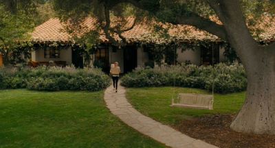 a woman walking down a path in front of a house