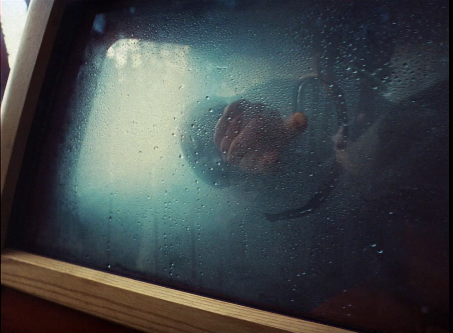 a person looking out of a window in the rain