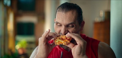 a man in a red shirt eating a piece of food