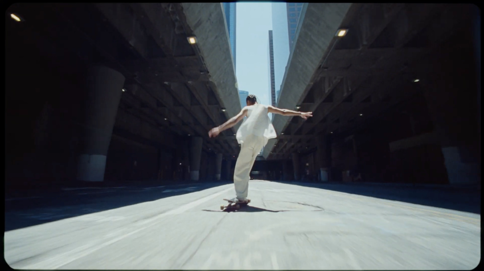 a man riding a skateboard down a street next to tall buildings