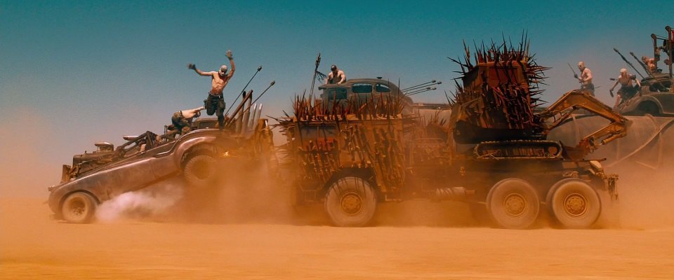 a group of trucks driving through a desert filled with dirt