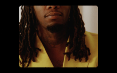 a man with dreadlocks wearing a yellow shirt