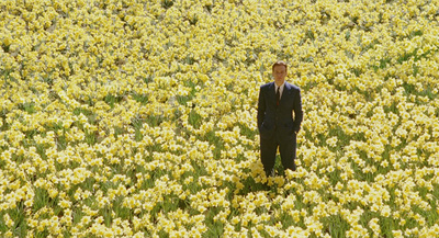 a man in a suit standing in a field of flowers