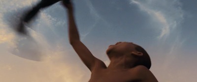 a shirtless man holding a tennis racquet up in the air