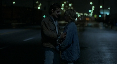 a man and a woman standing on a street at night