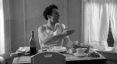 a man sitting at a table in front of a bottle of wine