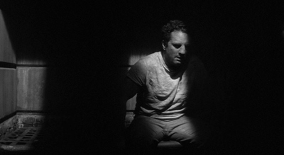 a man sitting in a dark room next to a wall