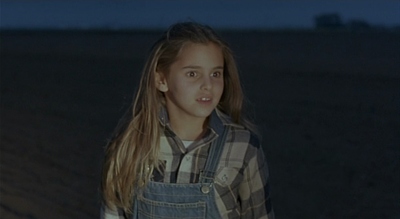 a young girl standing in a field at night