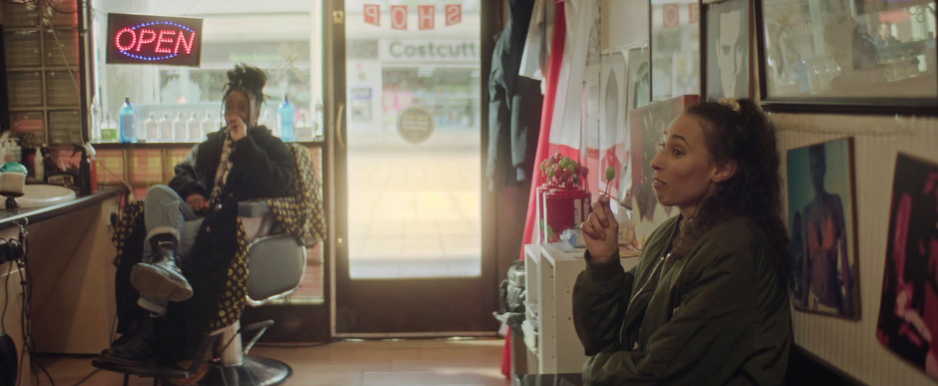 a woman standing in a barber shop next to a man