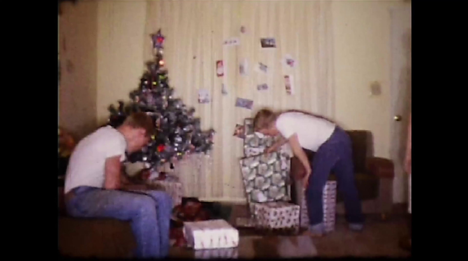 a man and a woman unwrapping gifts in a living room