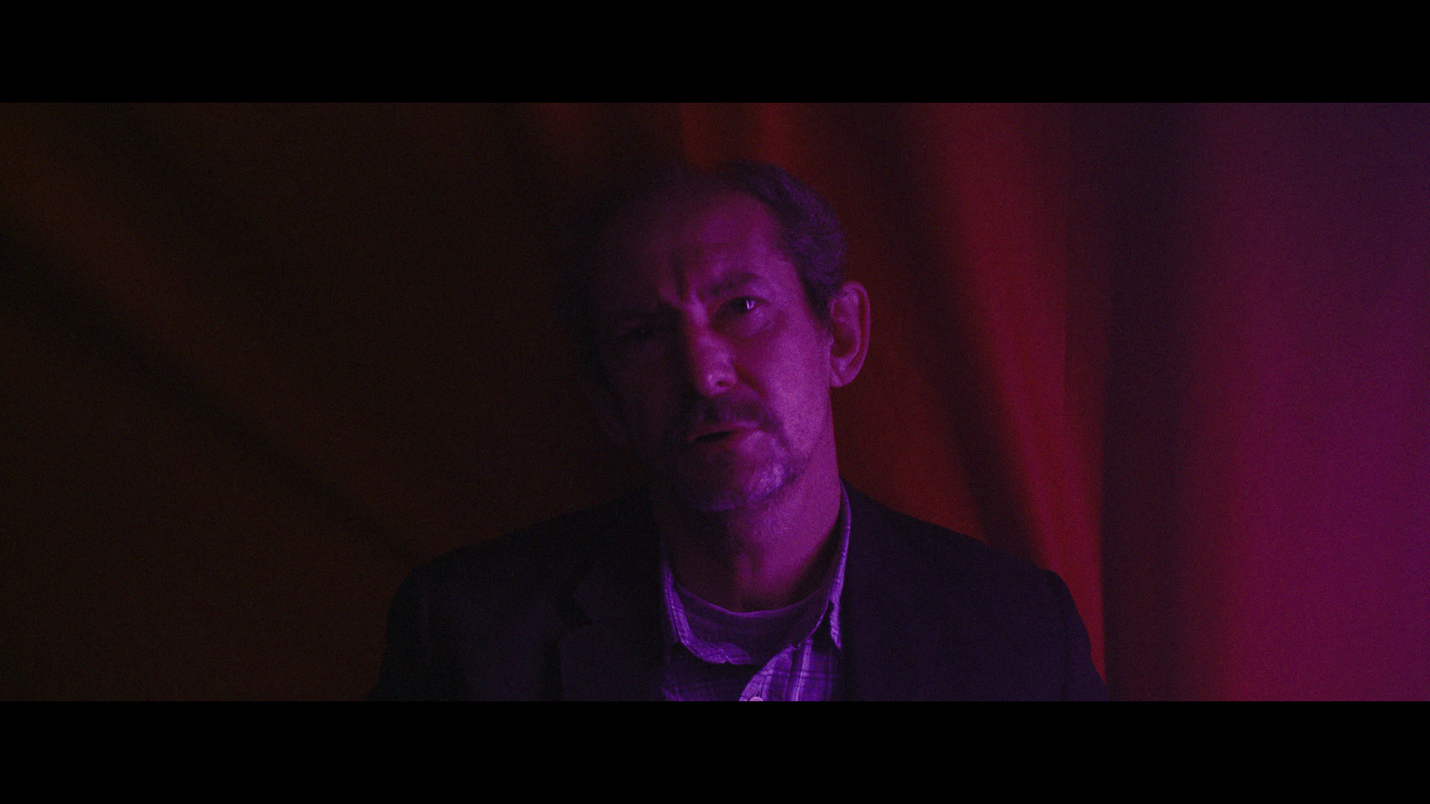 a man standing in front of a red curtain