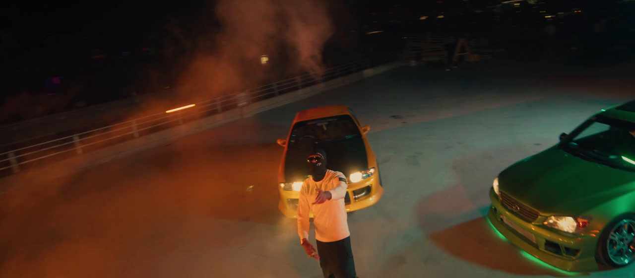 a man standing next to two cars in a parking lot