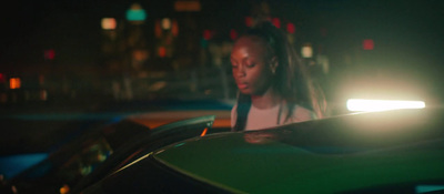 a woman standing next to a green car at night