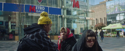 a group of people walking down a street next to tall buildings