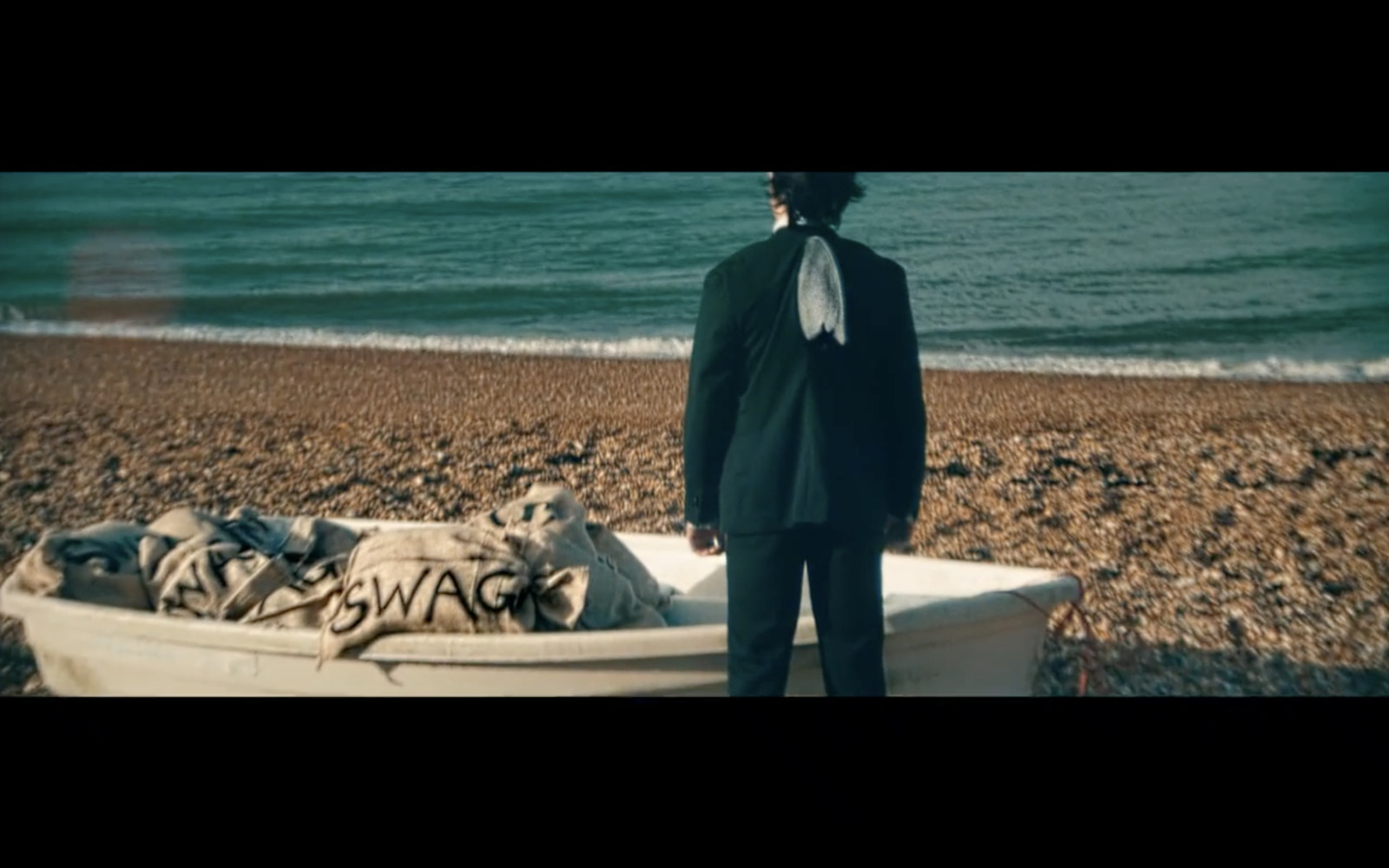 a man standing next to a boat on a beach