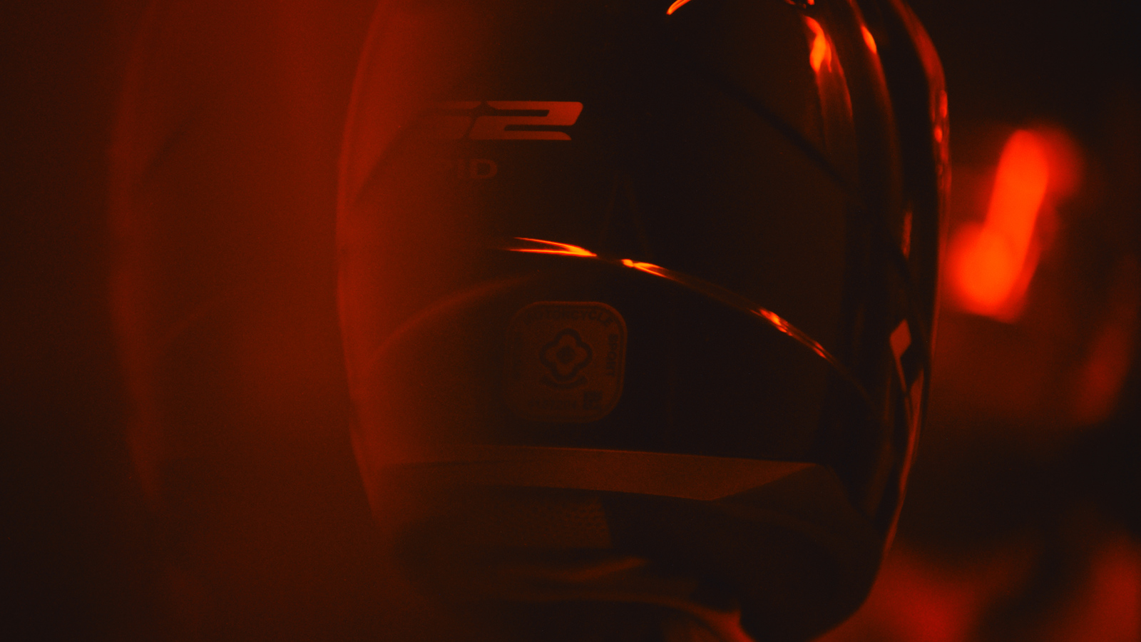 a close up of a helmet with a red light in the background