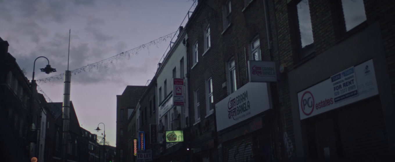 a city street with buildings and a string of lights