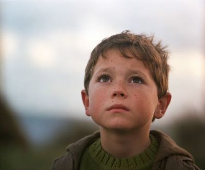 a young boy with a green sweater and a brown jacket