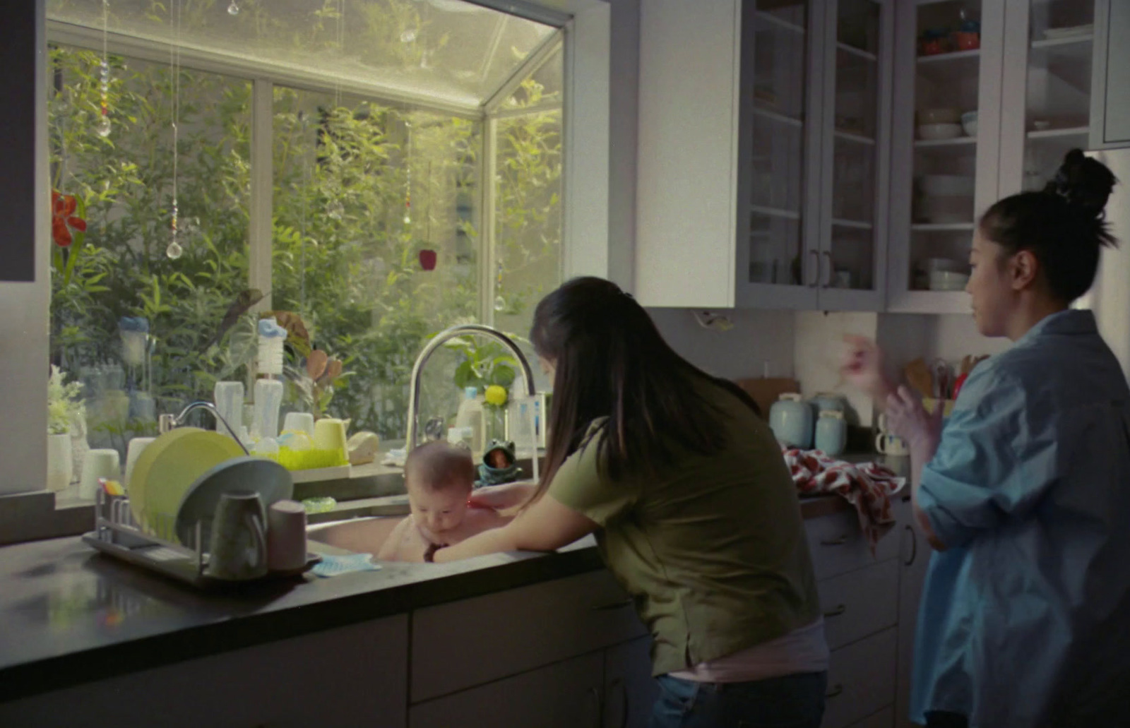 a woman and a baby in a kitchen sink