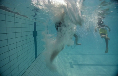 a person swimming in a pool with a large wave