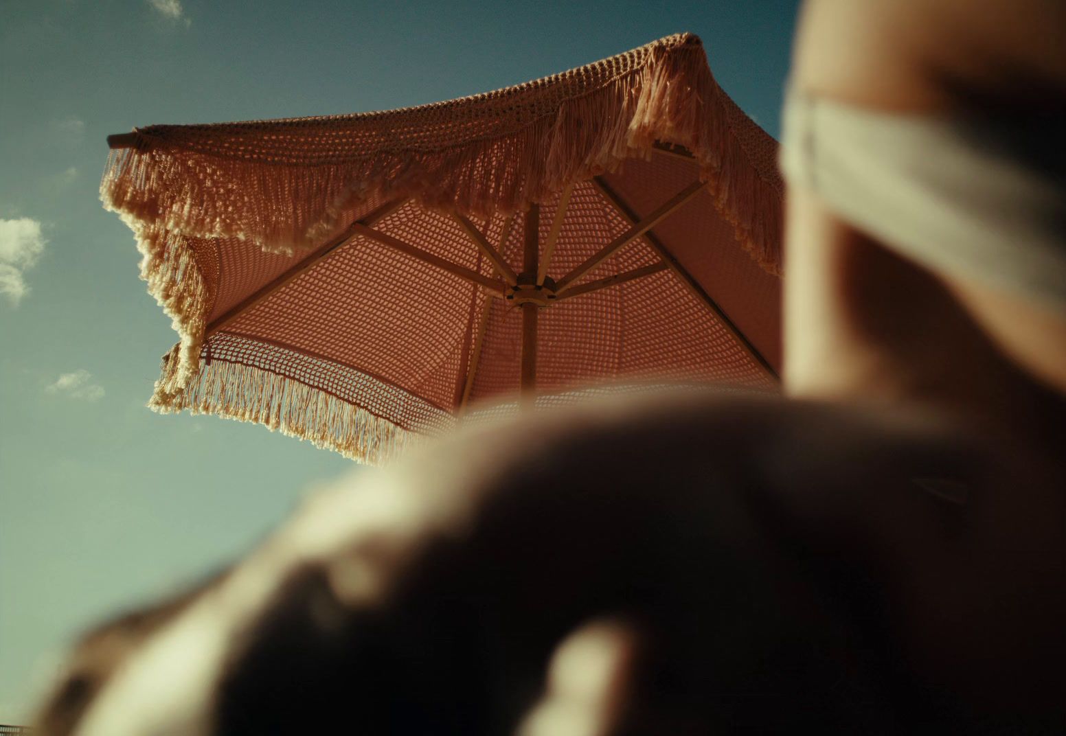 a person holding a brown umbrella under a blue sky