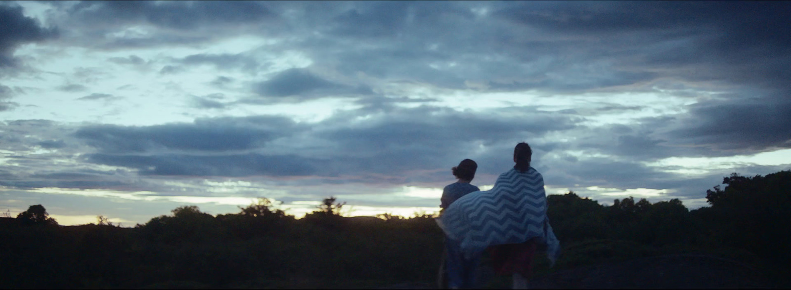 a couple of people standing under a cloudy sky